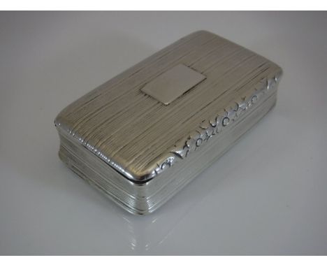 A George IV silver snuff box of waisted rectangular form with all over reeded decoration opening to reveal a gilt washed inte