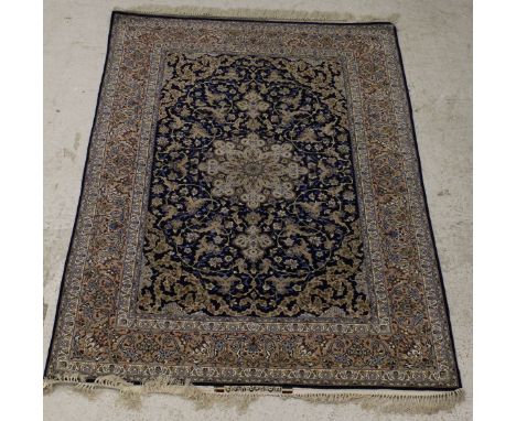 A 20th Century silk Persian rug with stylised central star motif on a blue ground with scrolling foliate and floral decoratio