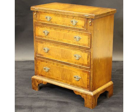 A walnut and banded bachelor's chest with fold-out top above four graduated drawers, raised on bracket feet