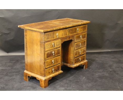 A walnut and feather-banded kneehole desk in the 18th Century manner, the quartered top over two drawers and central kneehole