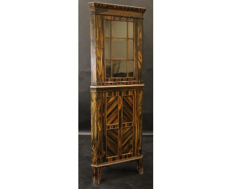 A 20th Century coromandel corner cabinet with single glazed door enclosing three shelves, raised on a base with panelled cupb