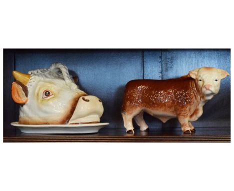 Staffordshire pottery cheese dome and cover formed as a cow's head, 18cm high, together with a Melba ware pottery figure of a