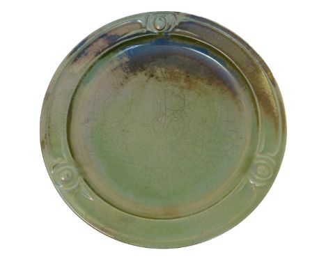 A Carter's Poole Pottery lustre charger designed by Owen Carter, the rim cast with a simple shield motif, glazed green lustre