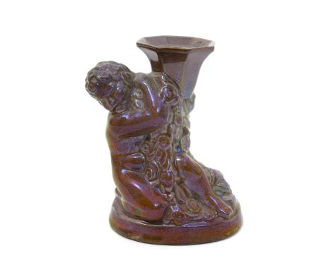 A rare Carter Stabler & Adams Poole Pottery lustre candlestick designed by Harold Brownsword,  modelled as a putti holding a 