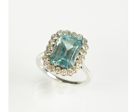 A blue zircon and diamond cluster ring, designed as a central trap cut zircon claw set within a border of twenty brilliant cu