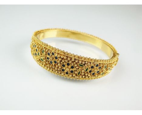 An 18ct yellow gold and enamel hinged bangle, designed as a tapering yellow gold bangle with bead and star embellishments wit