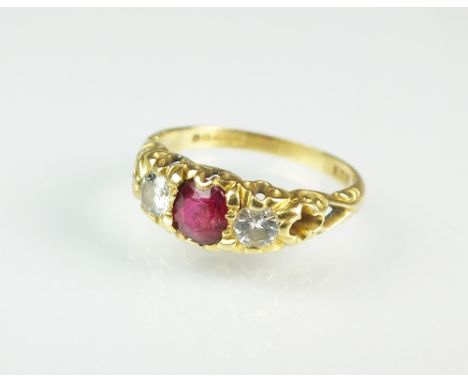 A late 19th century style 18ct gold three stone ruby and diamond ring, designed as a central oval mixed cut ruby flanked to e