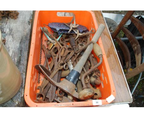 An orange crate of various hand tools, spanners, mole trap etc.