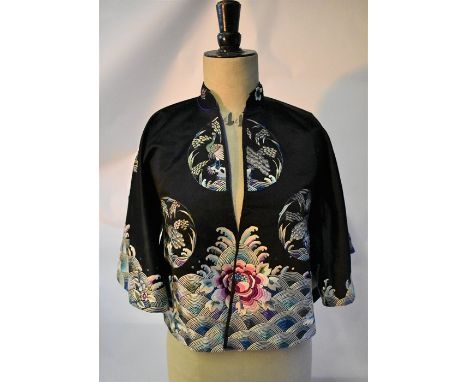 A vintage Chinese black silk embroidered jacket with rolling sea and roundels featuring peacocks perched in trees, an ivory s