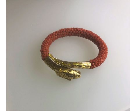 A Victorian coral and yellow gold serpent bangle, the yellow gold open-mouthed head and tail with chased decoration and inset