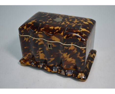 A Victorian tortoiseshell tea caddy with serpentine front, hinged cover with ivory veneered beading to two covered compartmen