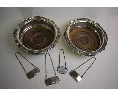 A pair of electroplated bottle coasters, three electroplated decanter labels and an enamel example inscribed 'Rose Geranium'