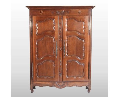 An 18th century French oak armoire, of large proportions, enclosed by a pair of panelled doors, above a shaped apron170w x 63