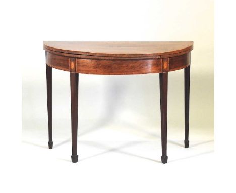 A George III mahogany, rosewood crossbanded and boxwood strung folding half round card table, the hinged top inlaid with a co