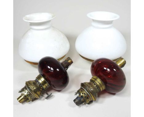 A pair of Victorian brass mounted peg oil lamps, each with a ruby glass font, brass fitting with Rd No 53/3 and opaque glass 