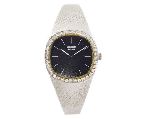 Seiko ladies white gold quartz wristwatch, black dial with baton hour markers and round brilliant cut diamond bezel, on integ