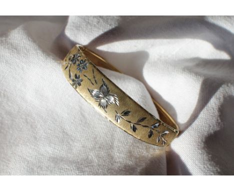 A 9ct yellow and white gold hinged bangle, decorated with flower heads and leaves, approximately 9.5 grams
