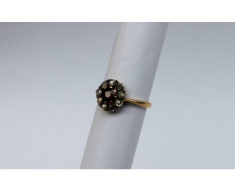 A ruby and diamond cluster ring, with a circular faceted ruby surrounded by nine rose cit diamonds to an 18ct yellow gold cla