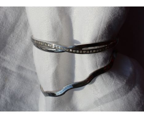 A 9ct white gold hinged bangle of wave form, together with a paste set 9ct white gold hinged bangle, approximately 16 grams