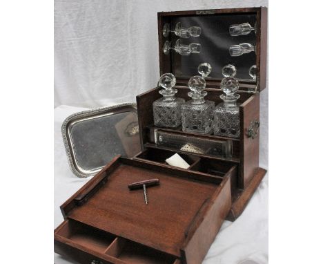 An early 20th century oak liquor cabinet, the hinged front enclosing a tray, three decanters, glasses, cribbage board and dra