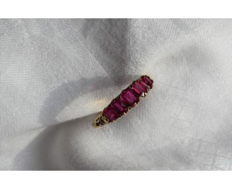 An 18ct yellow gold five stone ruby line ring, set with a central ruby at 5.4 x 4.8mm, two at 5.4 x 3.5 and two at 4.4 x 4mm,