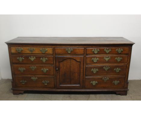 An 18th century North Wales oak dresser base, the rectangular planked top with cut corners, above a central drawer and cupboa