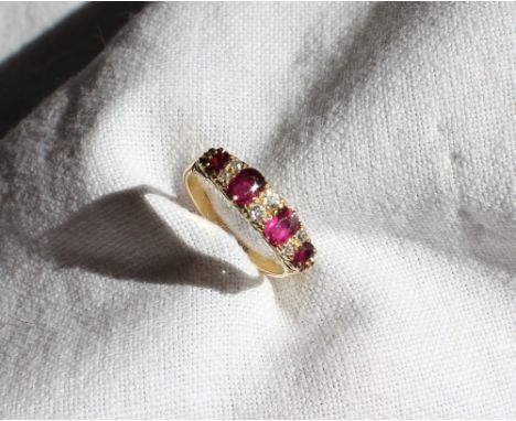 A ruby and diamond line ring, set with four rubies and six round old cut diamonds to a yellow gold claw setting and shank mar