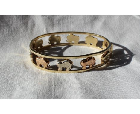 A three colour 9ct gold hinged bangle decorated with elephants, approximately 21 grams