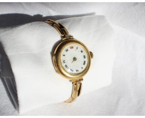 An 18ct yellow gold wristwatch with an enamel dial and Roman numerals on a yellow metal expanding bracelet marked 15ct, overa