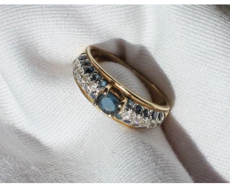 A sapphire and diamond ring, set with a central oval sapphire and twenty small round diamonds and ten round brilliant cut dia