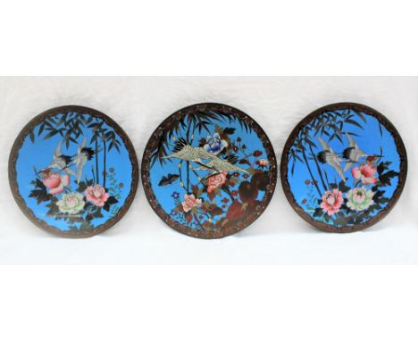 A set of three Japanese cloisonne enamel chargers decorated with cranes in flight with flowers and bamboo, to a scrolling bor