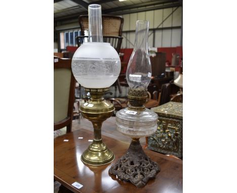 A Victorian cast iron oil lamp, clear glass reservoir; a brass oil lamp, twin burner, etched glass globular shade (2)