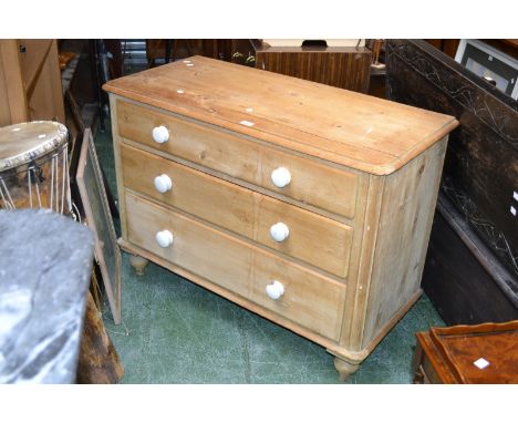A Victorian stripped pine chest of three graduated drawers, oversailing top, ceramic handles, turned feet. 77cm high x 107cm 
