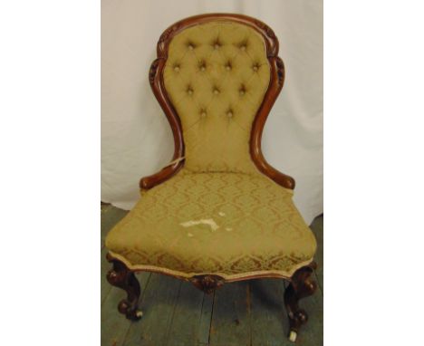 A Victorian spoon back upholstered salon chair with carved hardwood frame and button back, on porcelain castors