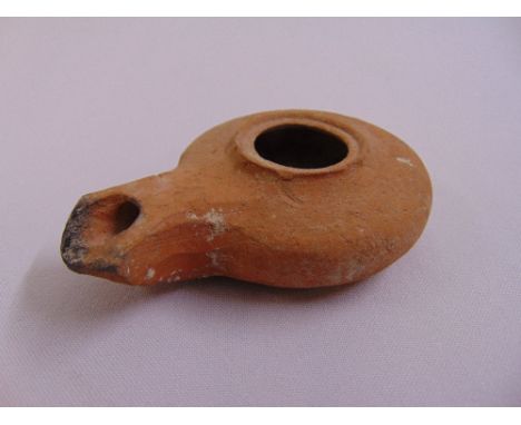 A Roman terracotta oil lamp of customary form