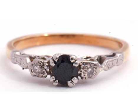 Sapphire and diamond three stone ring centring a round faceted dark sapphire flanked by small brilliant cut diamonds, each in