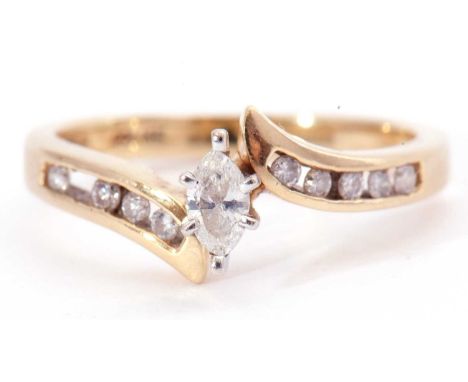 Modern diamond cross over ring centring a marquis diamond raised between diamond channel set shoulders (two diamonds missing)
