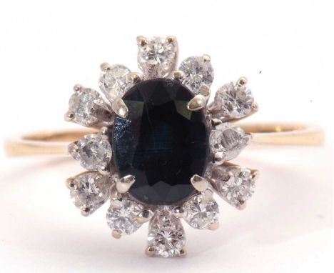 Modern sapphire and diamond cluster ring, the oval faceted dark sapphire within a small diamond two-tier surround, total diam