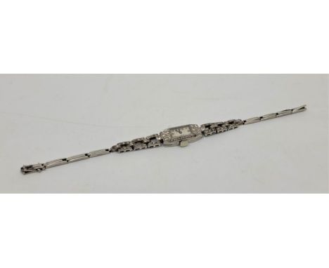 An Art Deco white metal and diamond set cocktail watch, manual movement, having rectangular white enamel Arabic numeral dial,