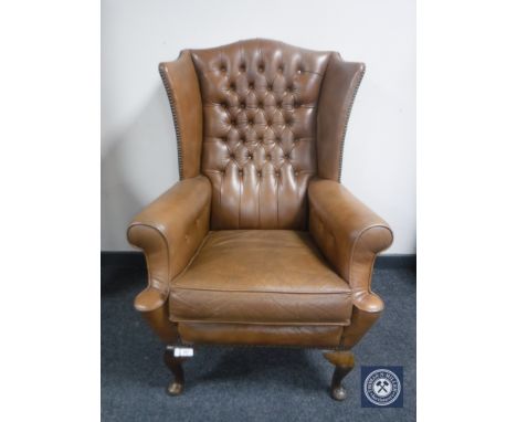 A brown button leather wing back armchair 