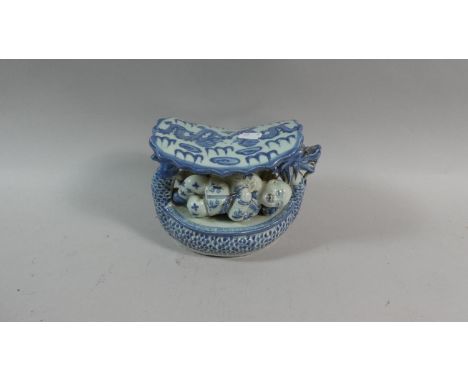 A Chinese Underglazed Blue and White Ceramic Opium Pillow in the form of a Dragon Boat With Recumbent Children, the Top Decor