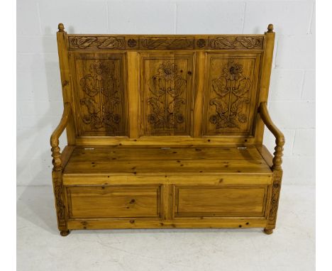 A vintage pine monk's bench with carved decorated back panels, with lift seat revealing storage, with acorn finials, 136cm wi