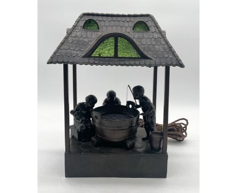 An Oswald Schimmelpfenning bronzed spelter figural table lamp, in the form of three children fishing from a water-barrel bene