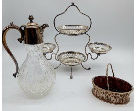 An antique silver plated epergne with pierced decorated dishes, a silver plated claret jug and a basket with red glass liner.