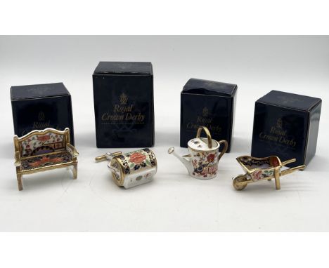 A collection of four Royal Crown Derby Miniatures comprising of a garden seat, wheelbarrow, garden roller and watering can - 