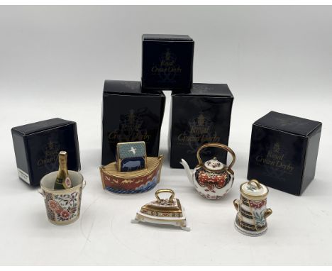 A collection of four Royal Crown Derby miniatures comprising of a champagne bottle and bucket, kettle, churn and iron along w