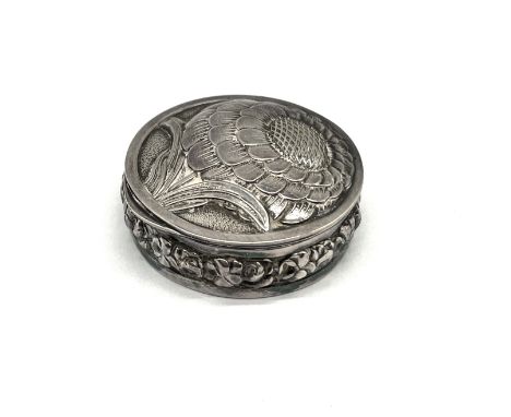 An unmarked silver lidded pill pot decorated with a flower