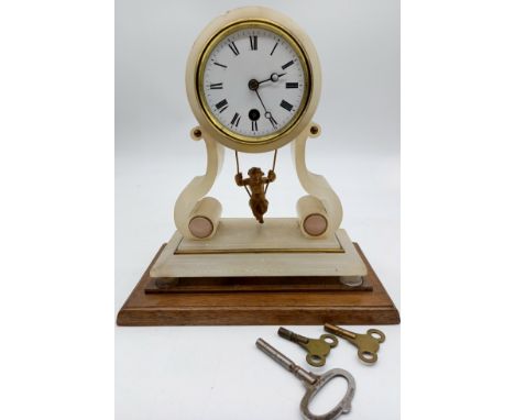 An antique French alabaster mantle clock, with cherub swinging pendulum, with keys.