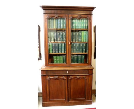 An attractive Victorian mahogany two door Bookcase, with moulded cornice over glazed doors with carved capitals,on a base wit