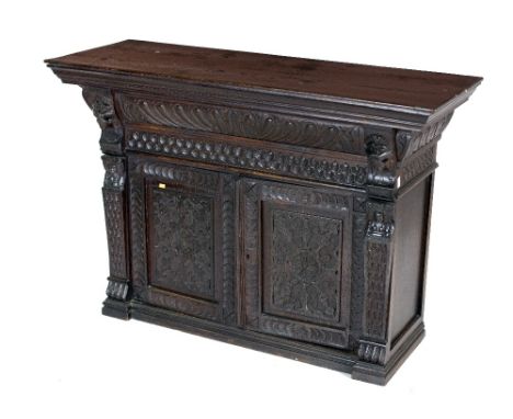 A 19th Century Cromwellian style oak Table Cabinet, with moulded cornice over carved decorated frieze above two panel doors f